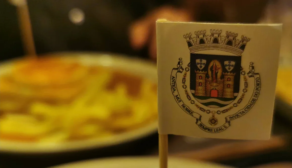 Francesinha do Capa na Baixa com uma bandeira de papel com o brasão da cidade do Porto